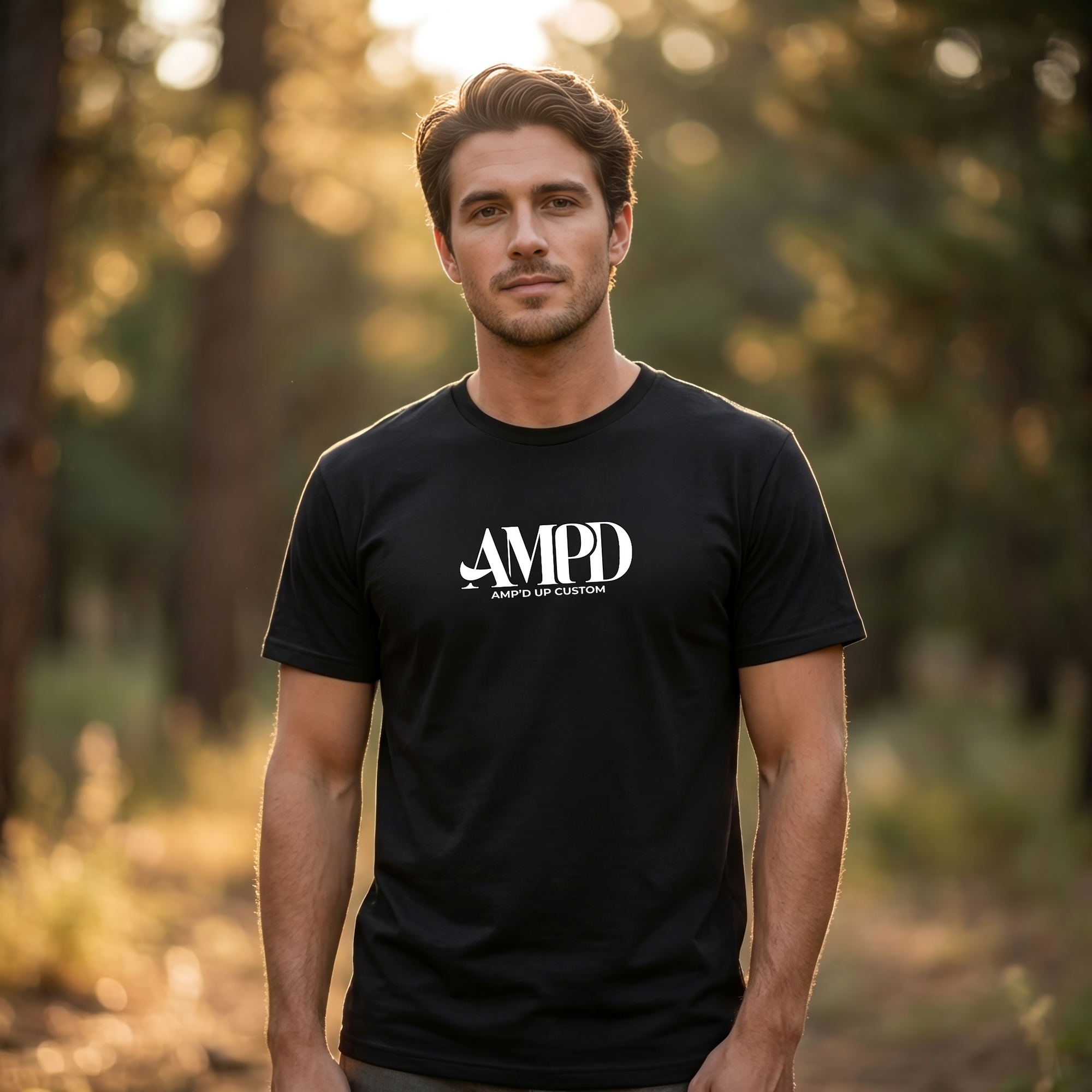 Man wearing a black t-shirt with 'AMPD' logo in a forest setting