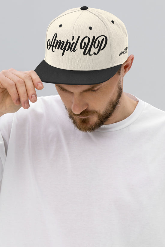 Man wearing Amp'd Up cursive 3D Puff Snapback Hat in cream and black for stylish headwear