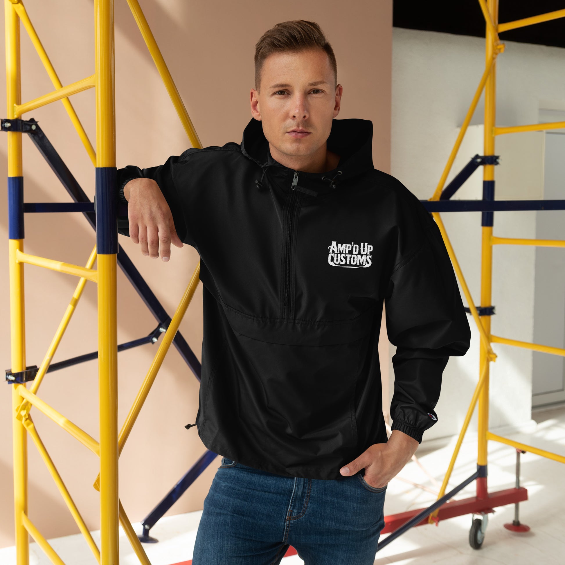Amp'd Up Custom Embroidered Champion Packable Jacket worn by a man against a construction backdrop