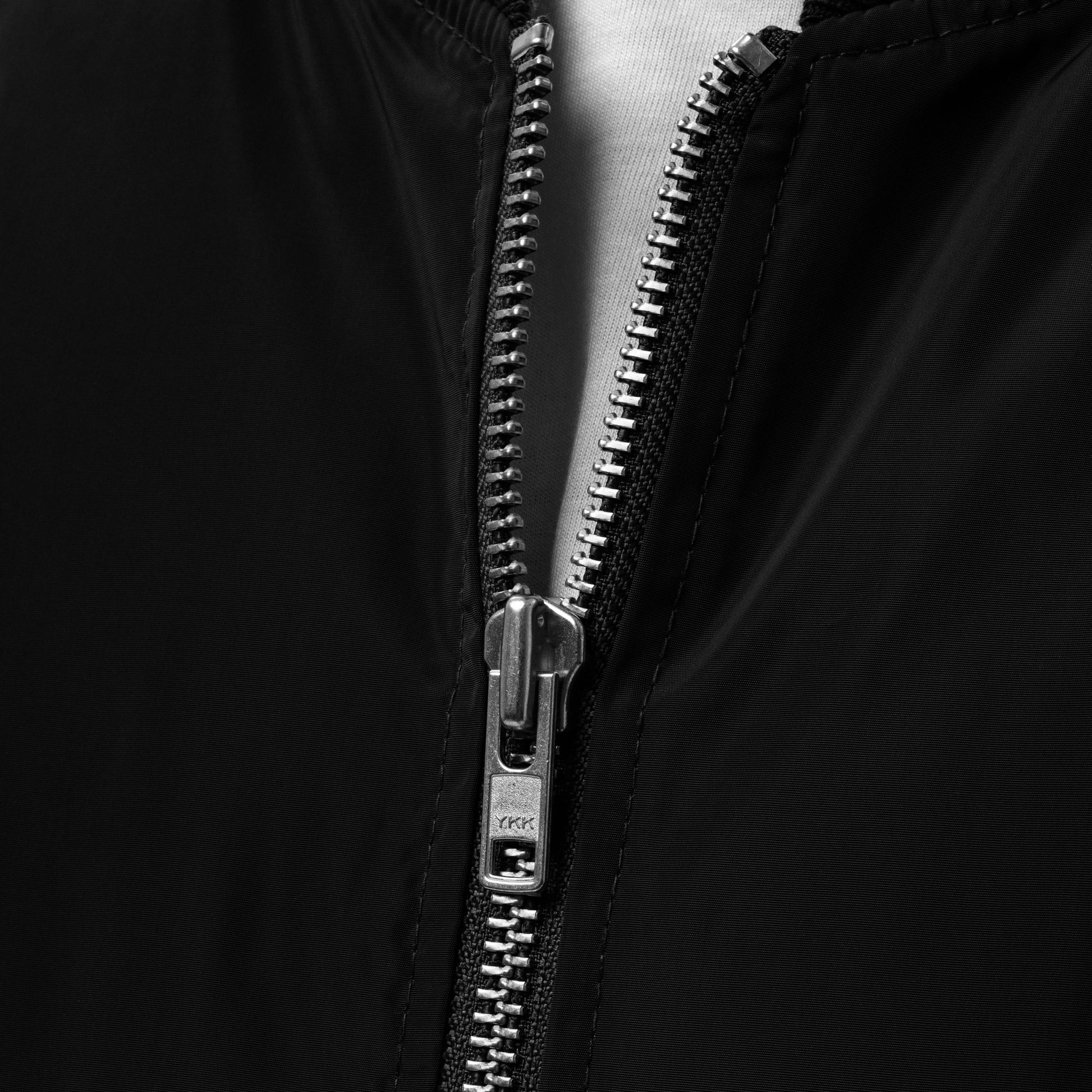 Close-up of the zipper on Ampd Up Custom Premium recycled bomber jacket in black