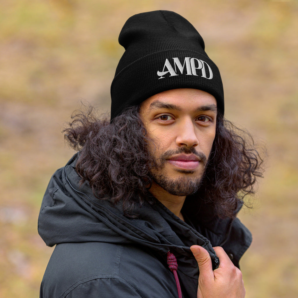 Amp'd Up Logo Cuffed Beanie in black worn by a man with curly hair outdoors