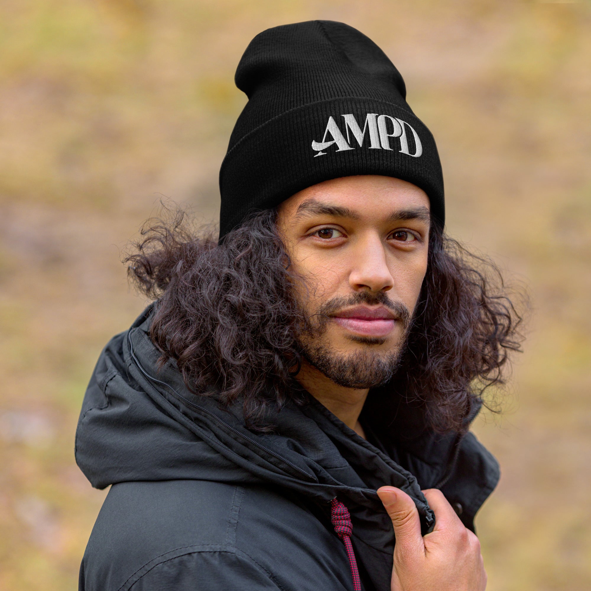 Amp'd Up Logo Cuffed Beanie in black worn by a man with curly hair outdoors