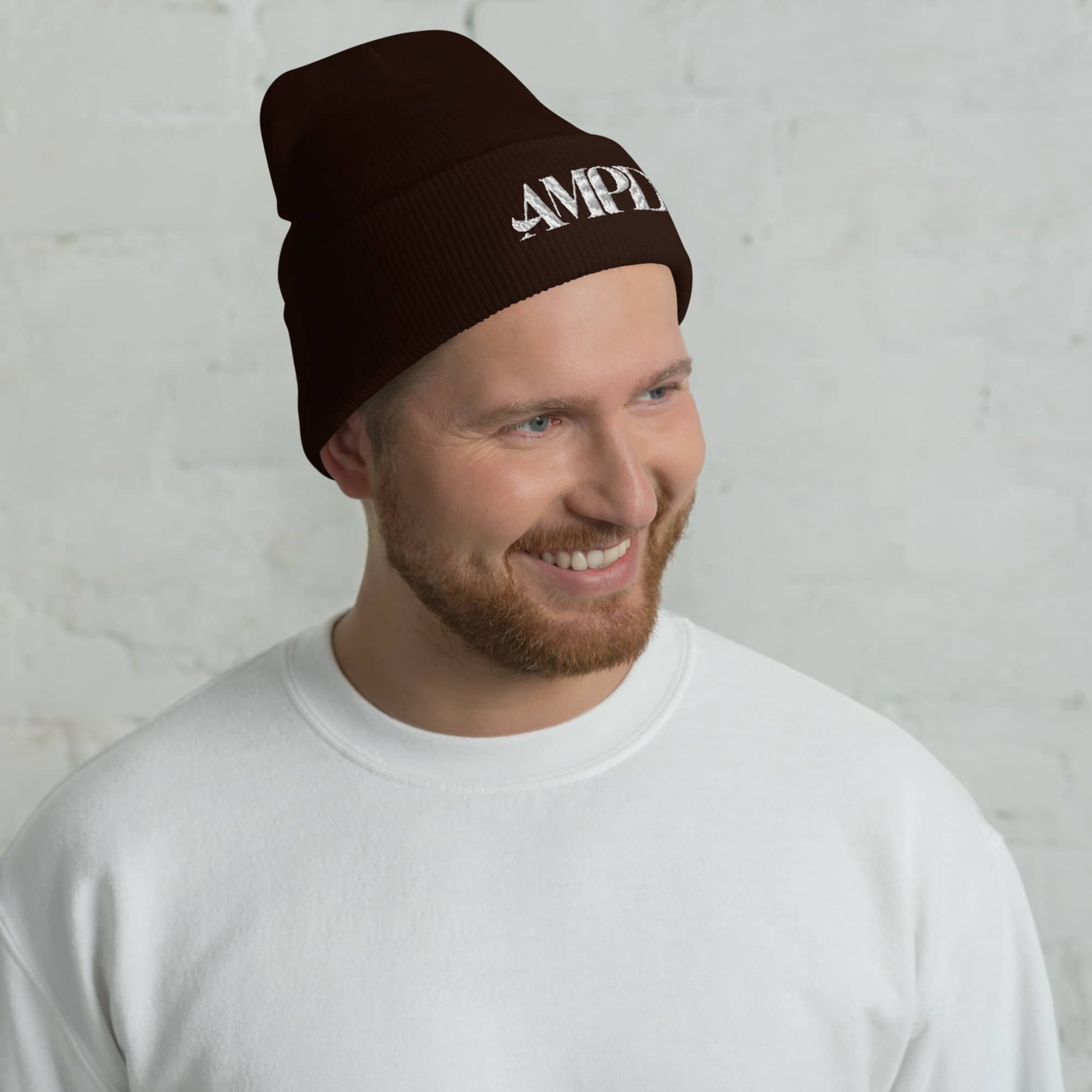 Amp'd Up Logo Cuffed Beanie in brown worn by a smiling man with a white sweatshirt
