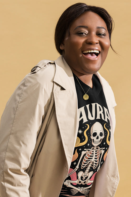 Smiling woman wearing Amp'd Up Custom black AURA Sweatshirt with skeleton graphic and beige jacket