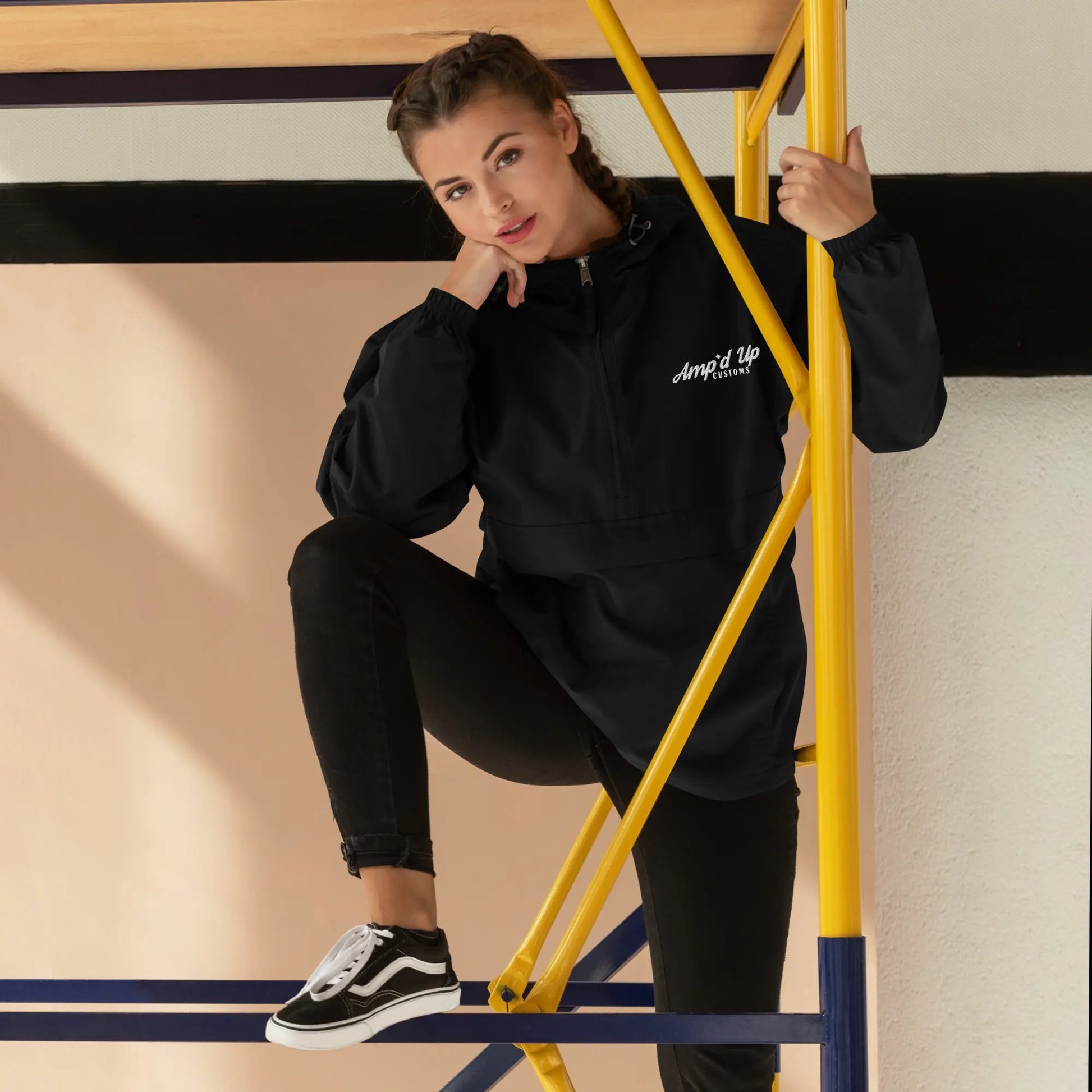 Fashionable model wearing the Amp'd Up Embroidered Champion Packable Jacket in black, styled with black jeans